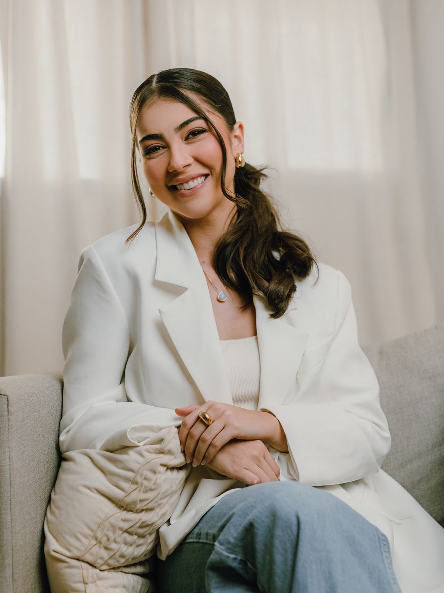 Jordana Feitosa, psicóloga clínica em Mossoró-RN, sentada em um sofá claro, sorrindo para a câmera.